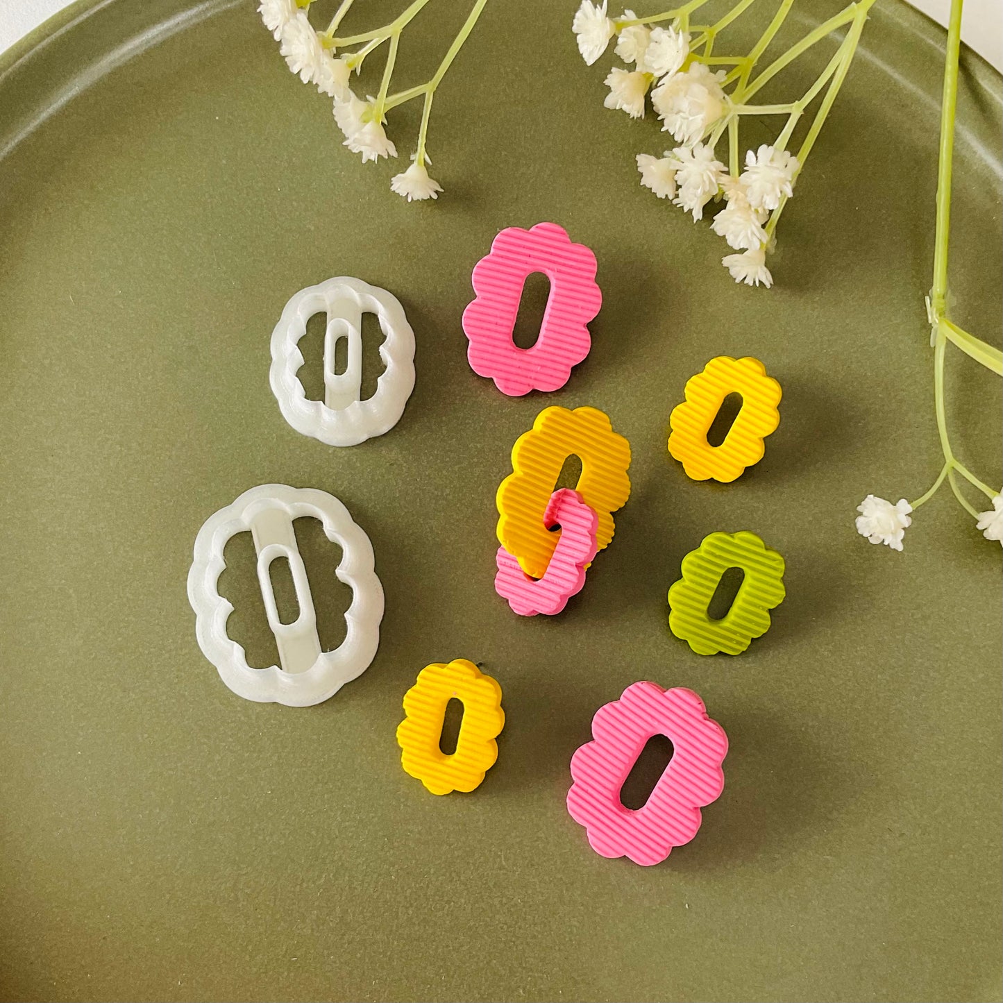 flower hoop shape for earrings next to polymer clay cutters on a plate
