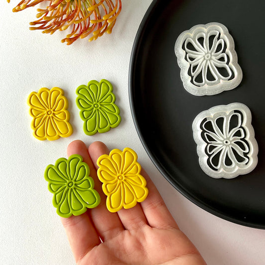retro style flower cutters for polymer clay on a hand next to a plaete