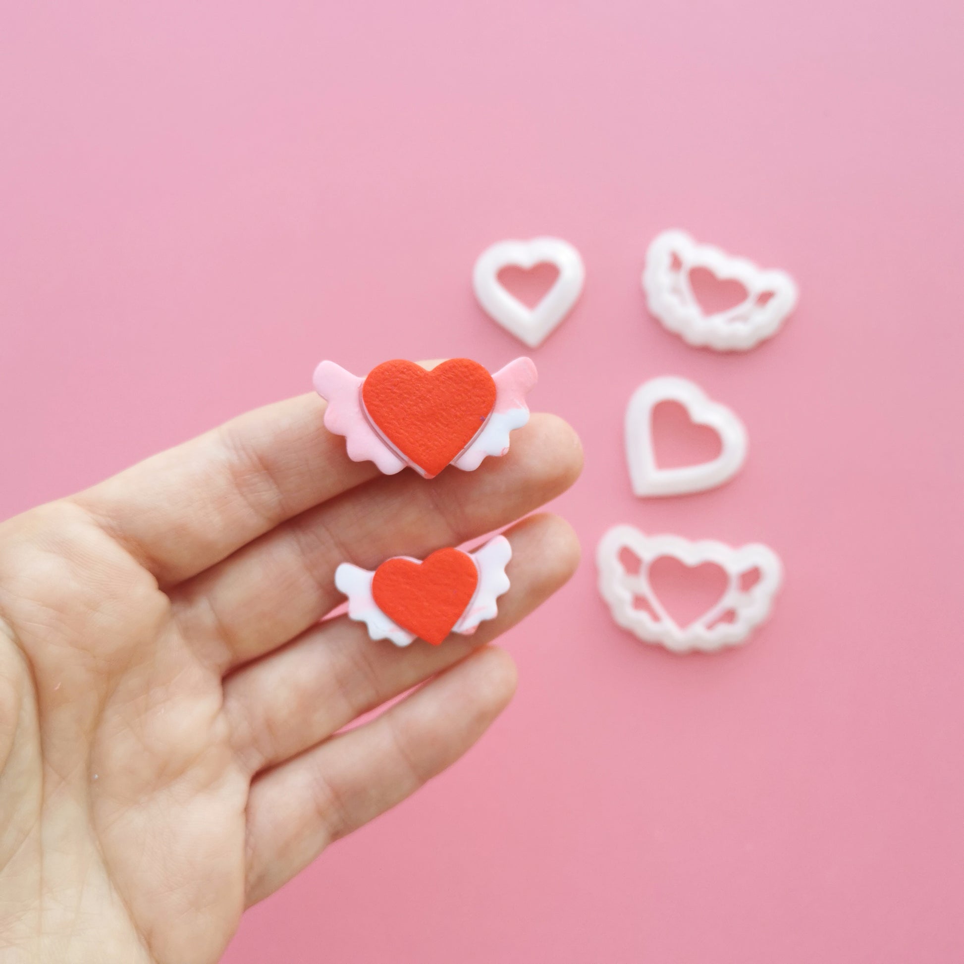 flying hearts cutters for clay on a hand on a pink background