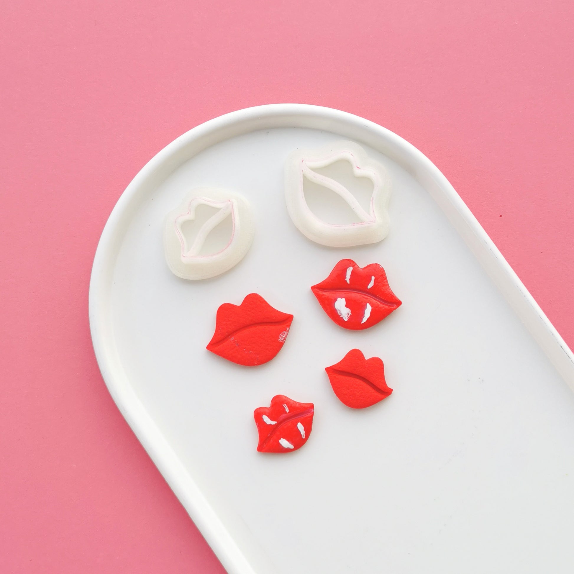 Two lip shaped polymer clay cutters and four red lip shaped polymer clay earrings