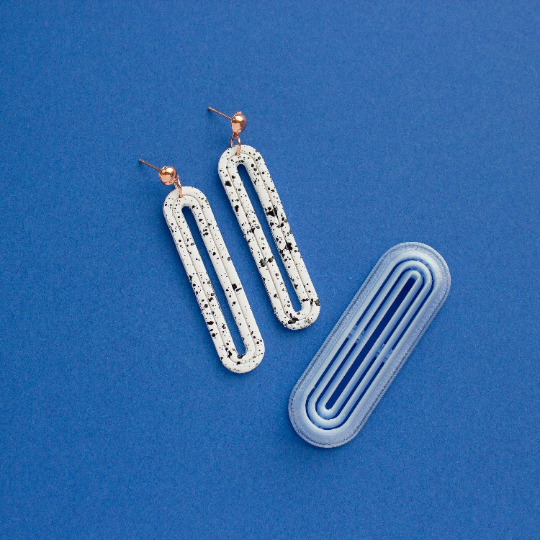 Long oval donut cutter and two donut polyemer clay earrings on a blue background