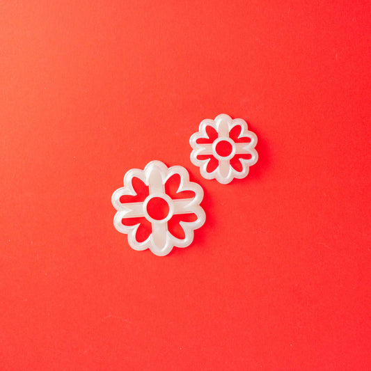 2 daisy shape polymer clay cutters on a red background.