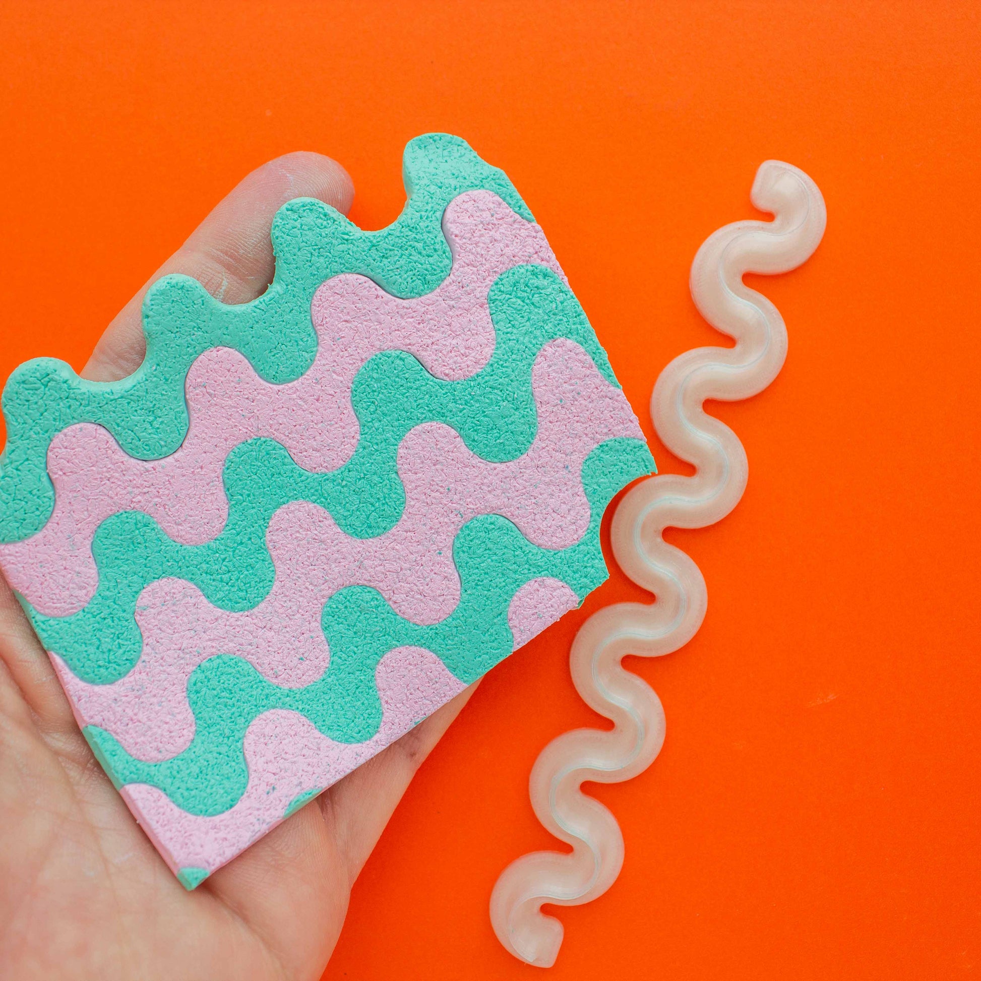 polymer clay colorful slab and one wiggle 3d printed blade in an orange background