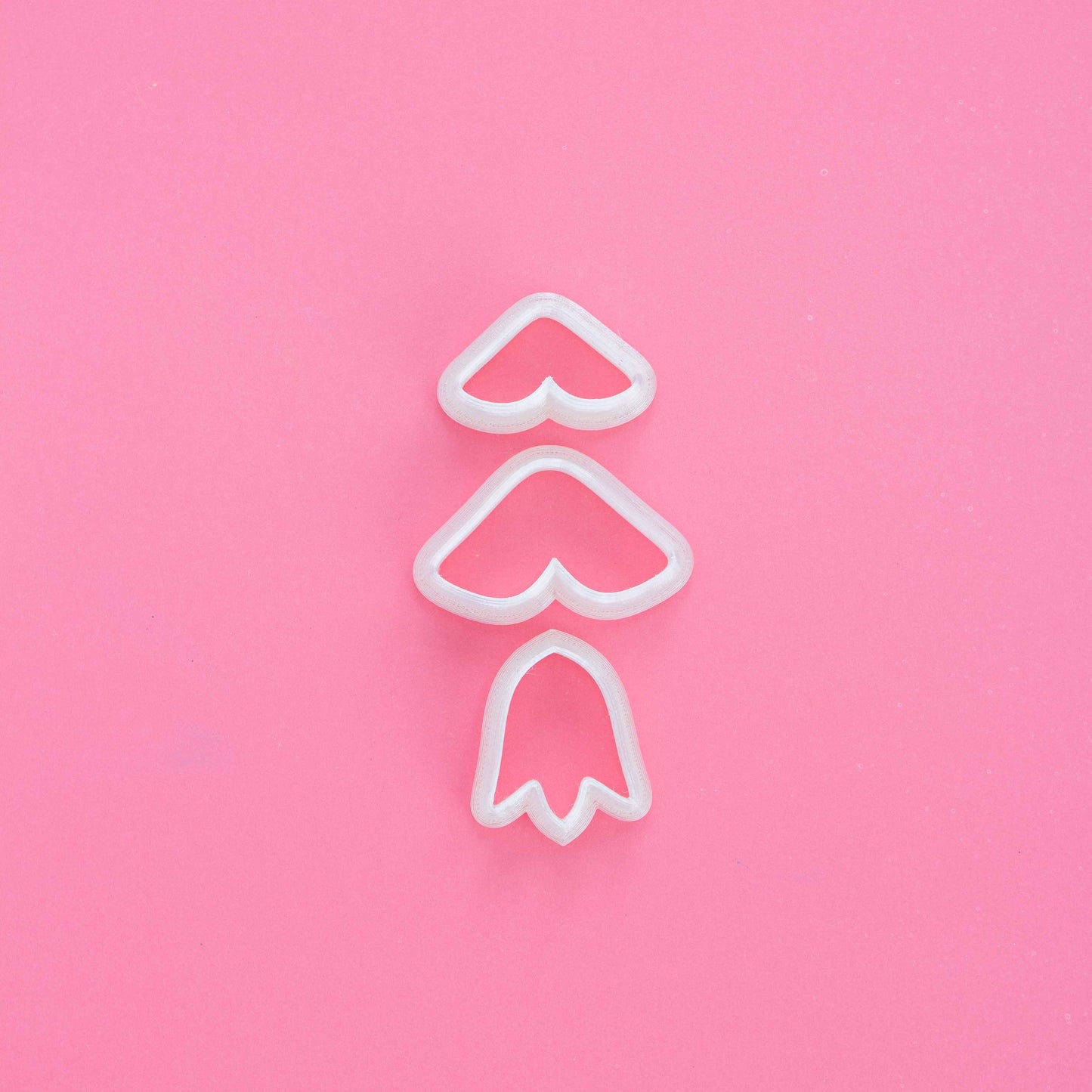 3 tulip shape clay cutters on a pink background