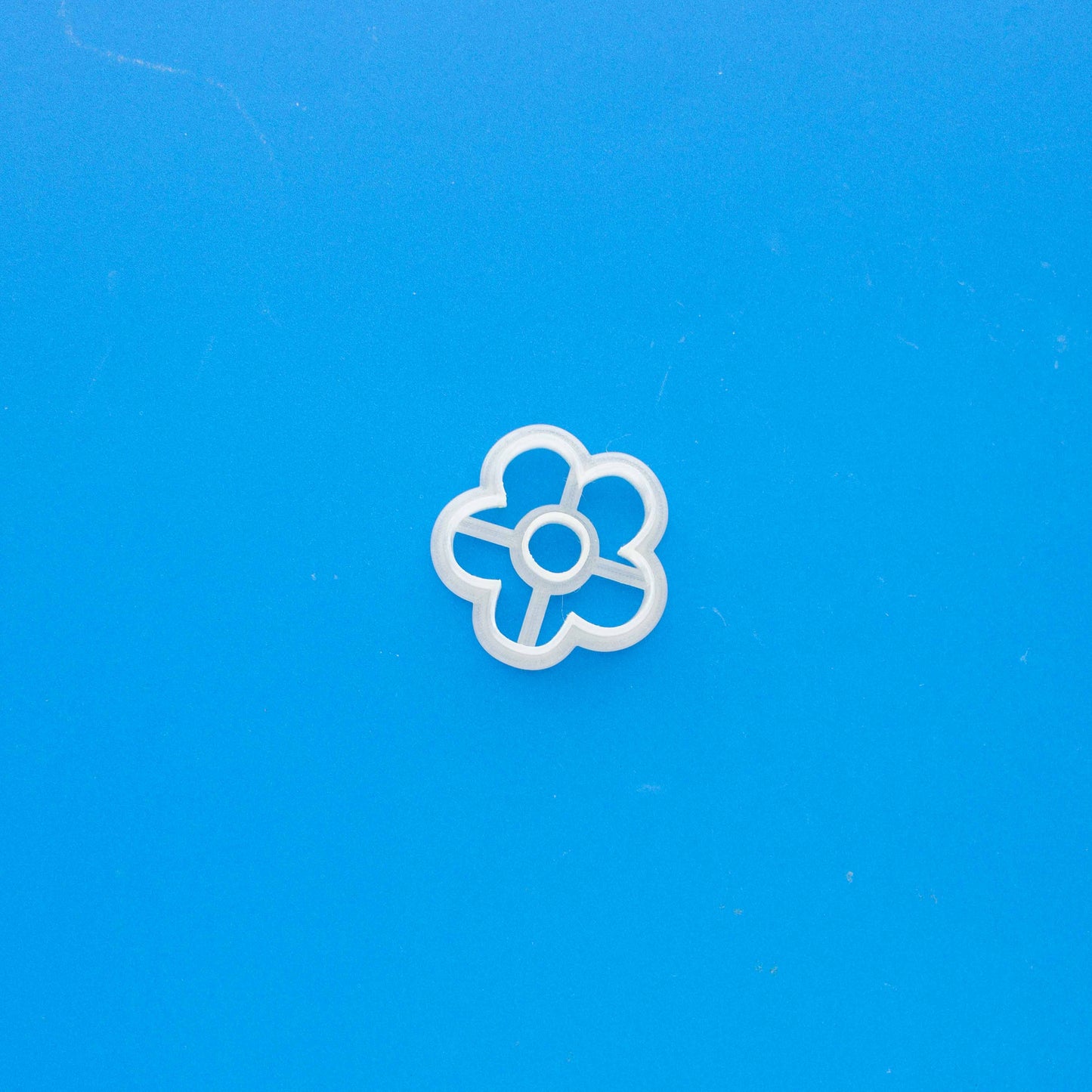 Daisy polymer clay cutter on a blue background