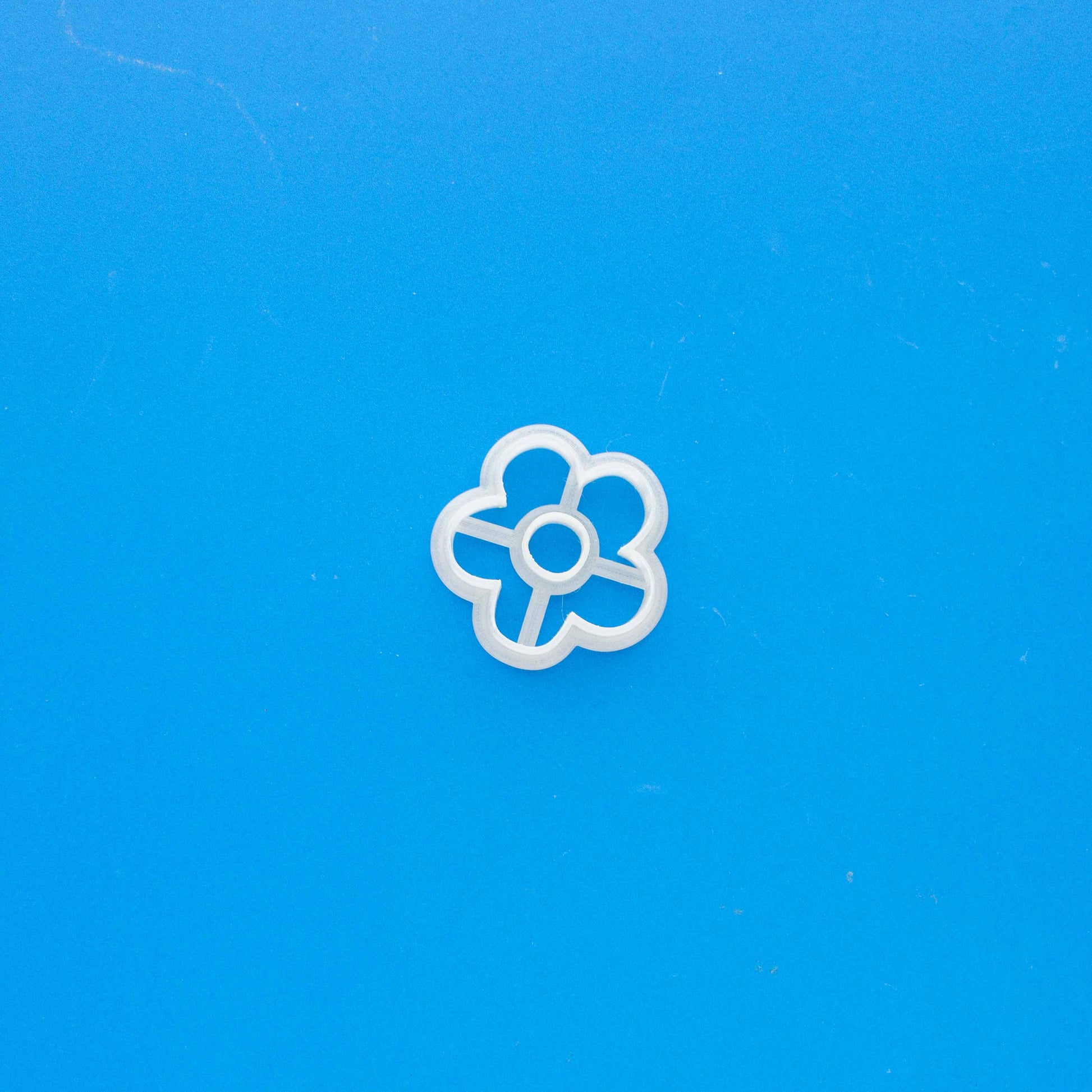 Daisy polymer clay cutter on a blue background