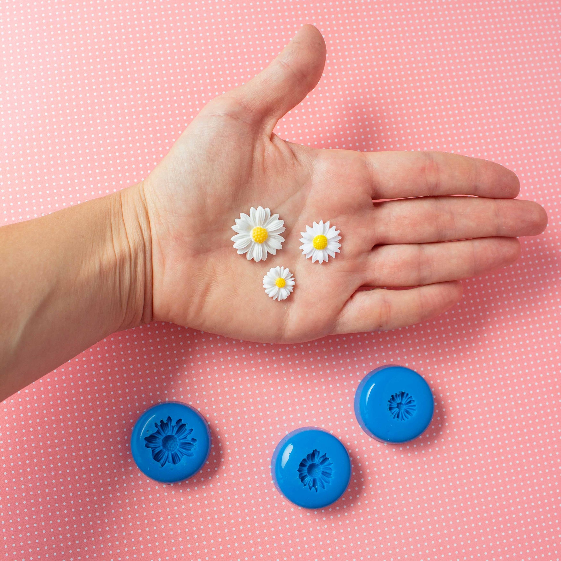 3 daizies on a hand and a set of 3 flower silicone molds in a pink polka dots background.