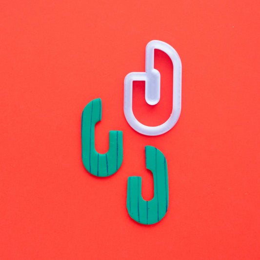 abstract oval cutter with two green earings in red background 