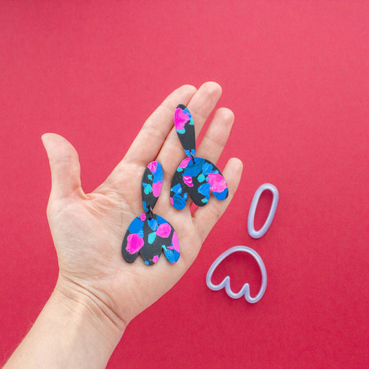 2 abstract flower polymeric clay earring sets on a hand.