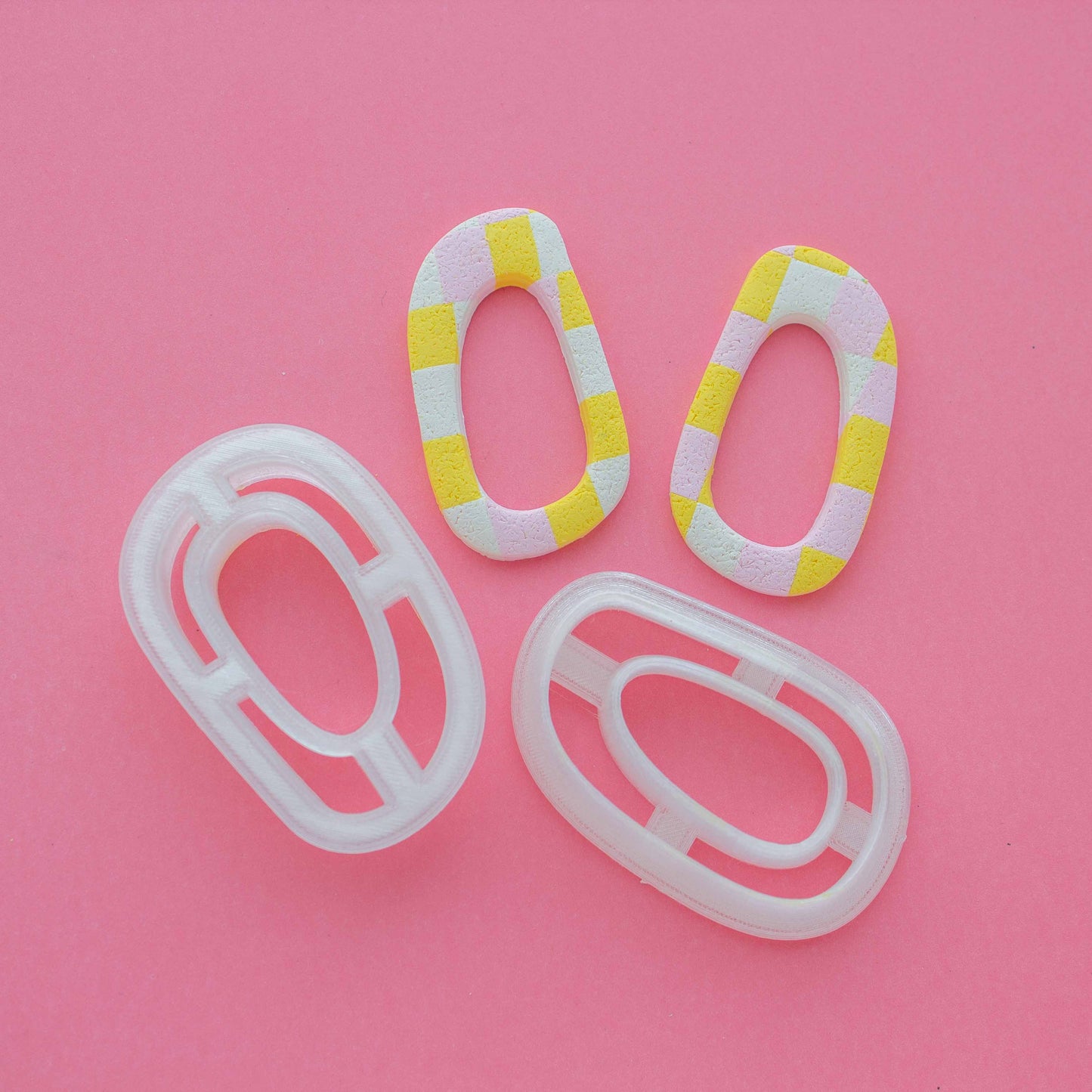 Two abstract hoop earrings and polymer clay cutters in a pink background