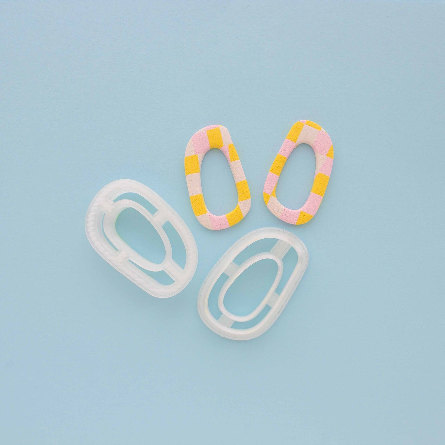 Two abstract hoop earrings and polymer clay cutters in a light blue background