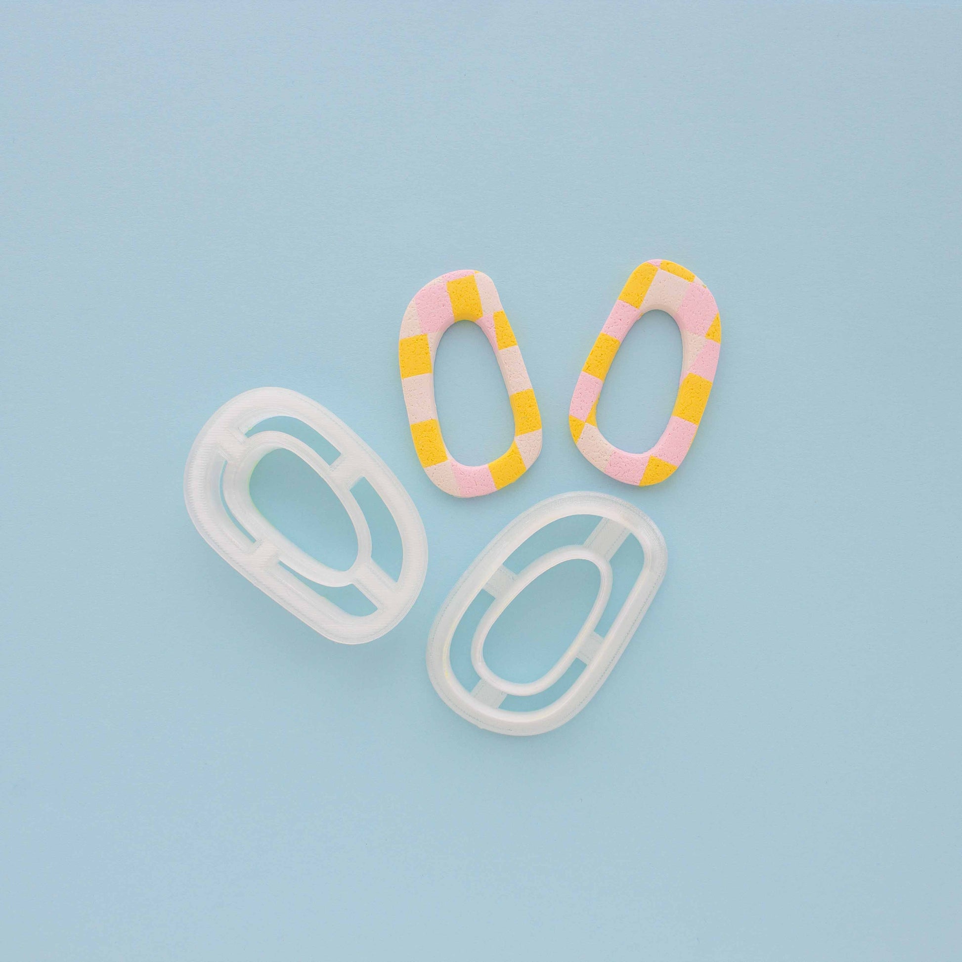 Two abstract hoop earrings and polymer clay cutters in a light blue background