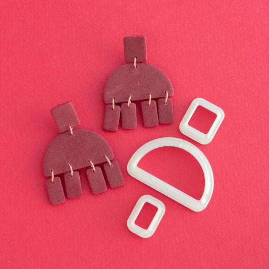 Geometric drop earring and polymer clay cutters on a red background