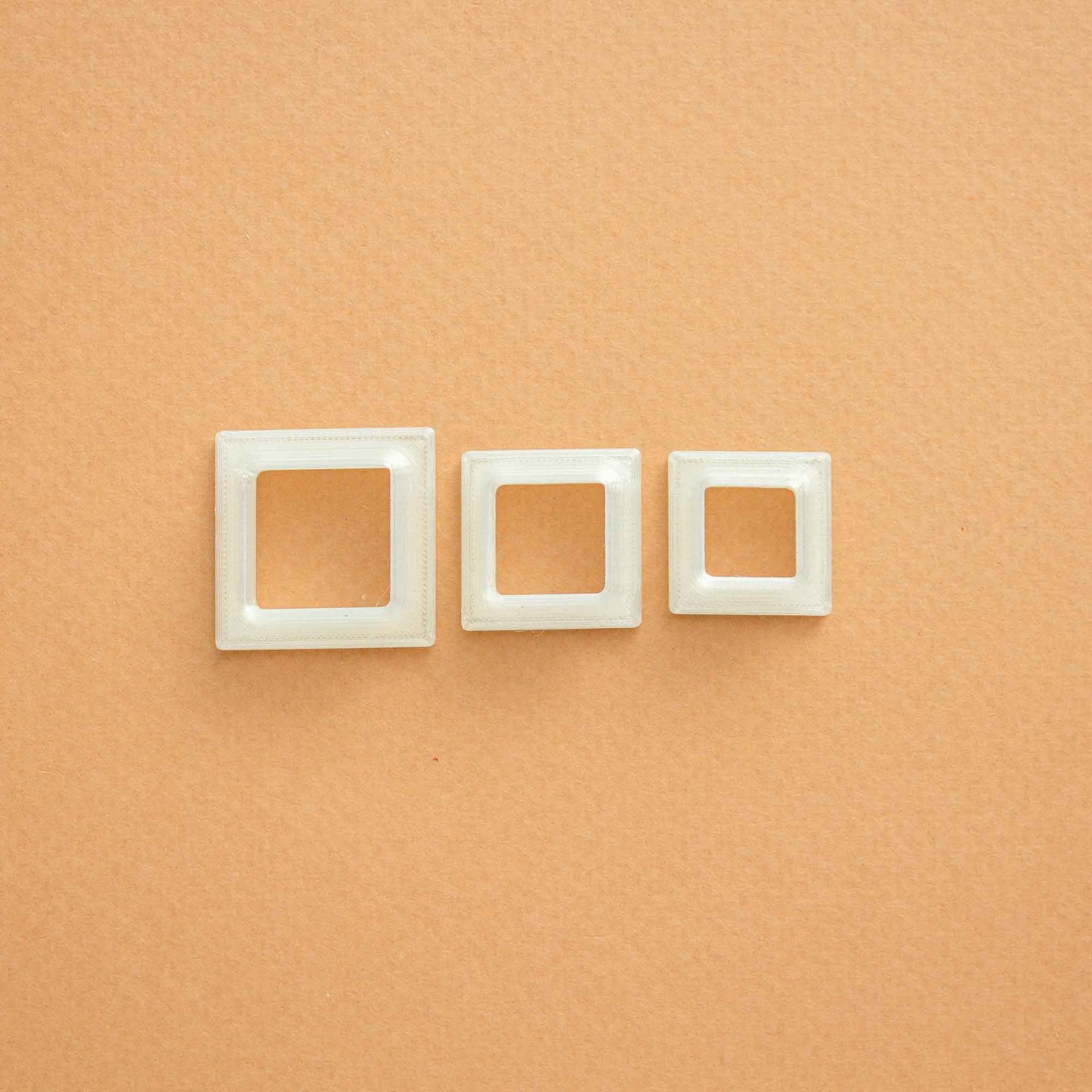 3 small square polymer clay cutters on a light brown background