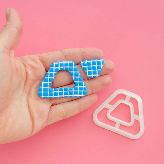 One trapezoid donut polymer clay cutter and two polymer clay earrings on a hand