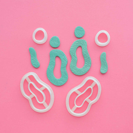 organic shapes textured polymer clay shapes next to organic shapes cutters for clay on a dusty pink background