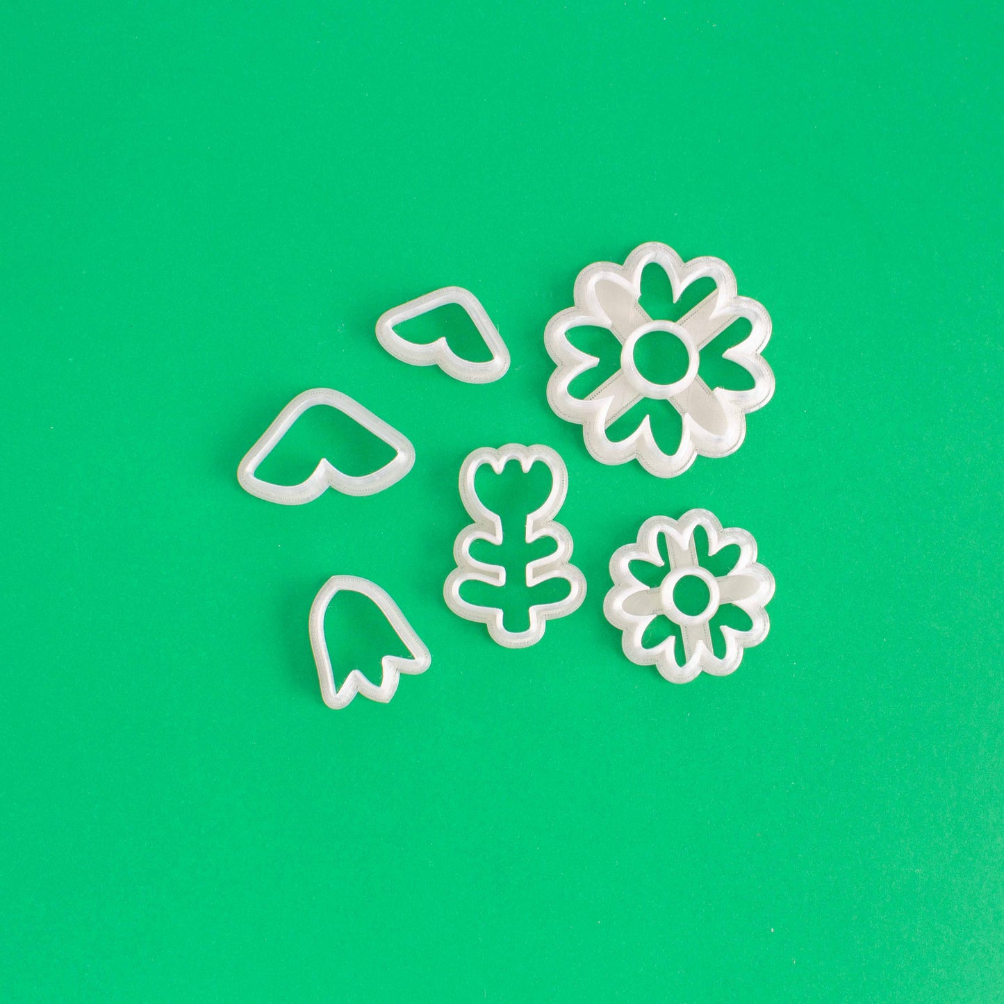 Flower shape clay cutters on a green background.