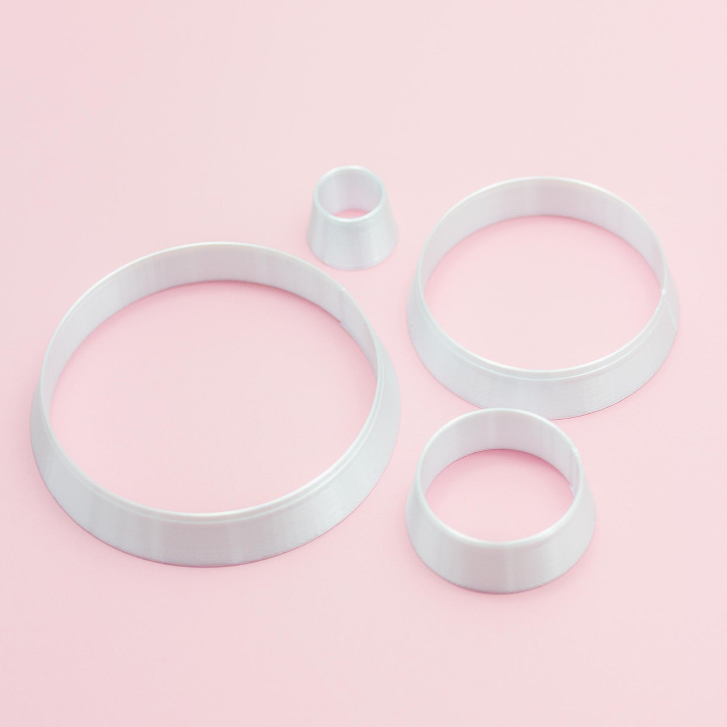 four different circle sizes polymer clay cutters on a pink background