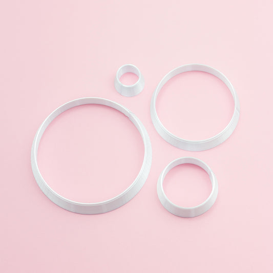 four different circle sizes polymer clay cutters on a pink background