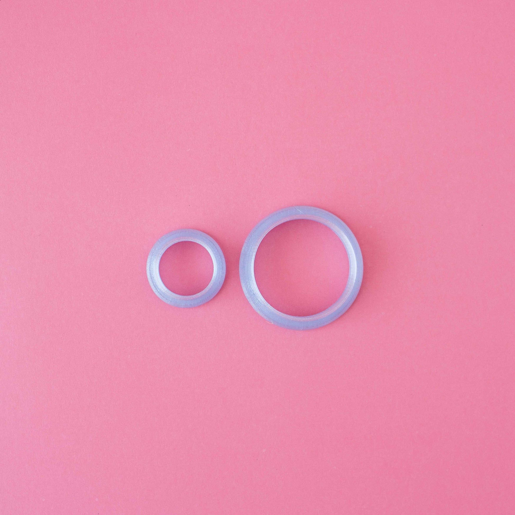 Two different circle polymer clay cutter sizes in a pink background.