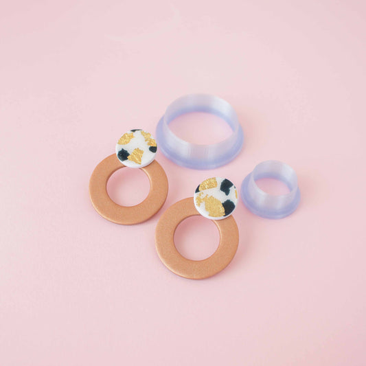 Two different circle polymer clay cutters sizes in a pink background.