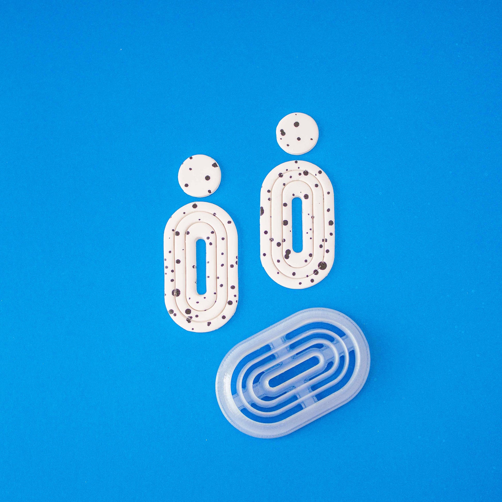 Donut cutter and 2 donut polymer clay earrings on a blue background.