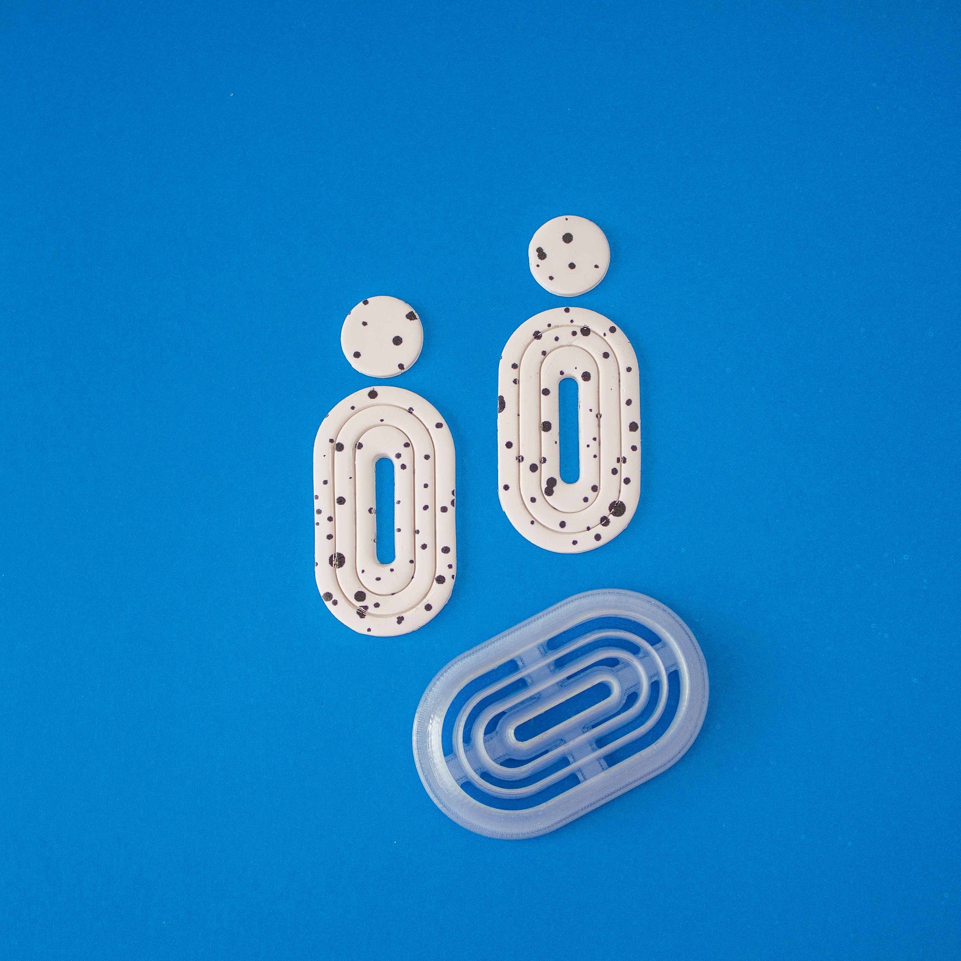 Donut cutter and 2 donut polymer clay earrings on a blue background.