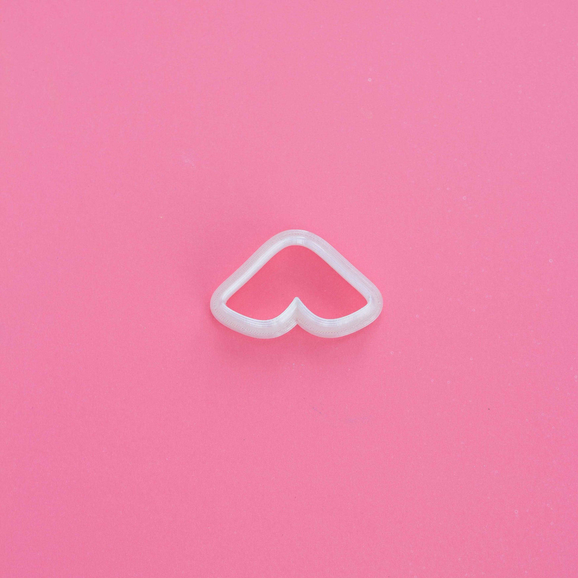 Double leaf clay cutter on a pink background.