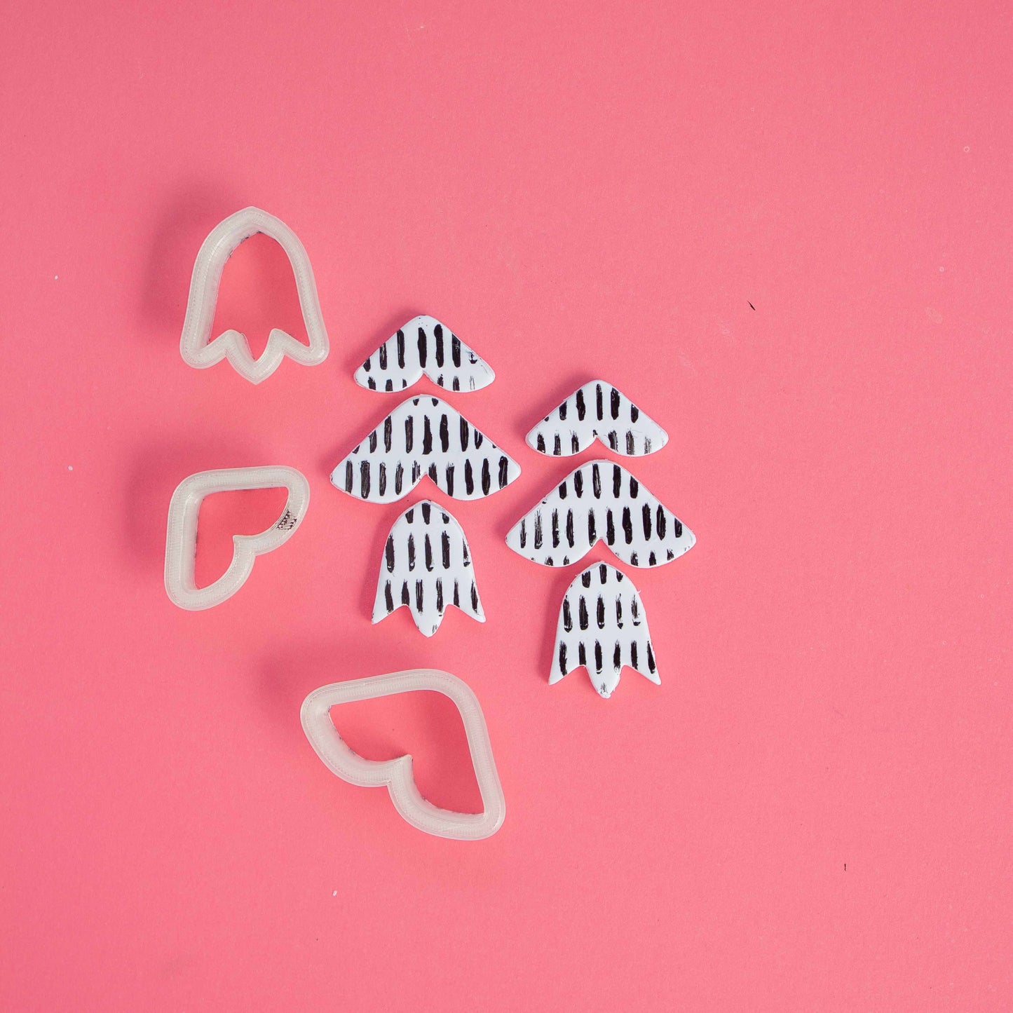 3 tulip shape clay cutters and clay on a pink background